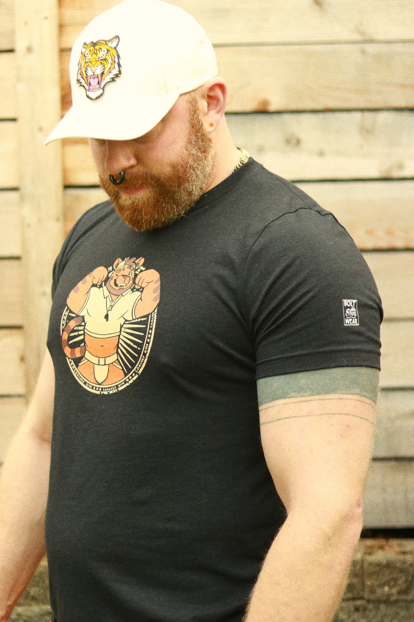 full body shot of ginger wearing white hat featuring a tiger and black heather tshirt featuring a flexing tiger coach and bolt-wear logo