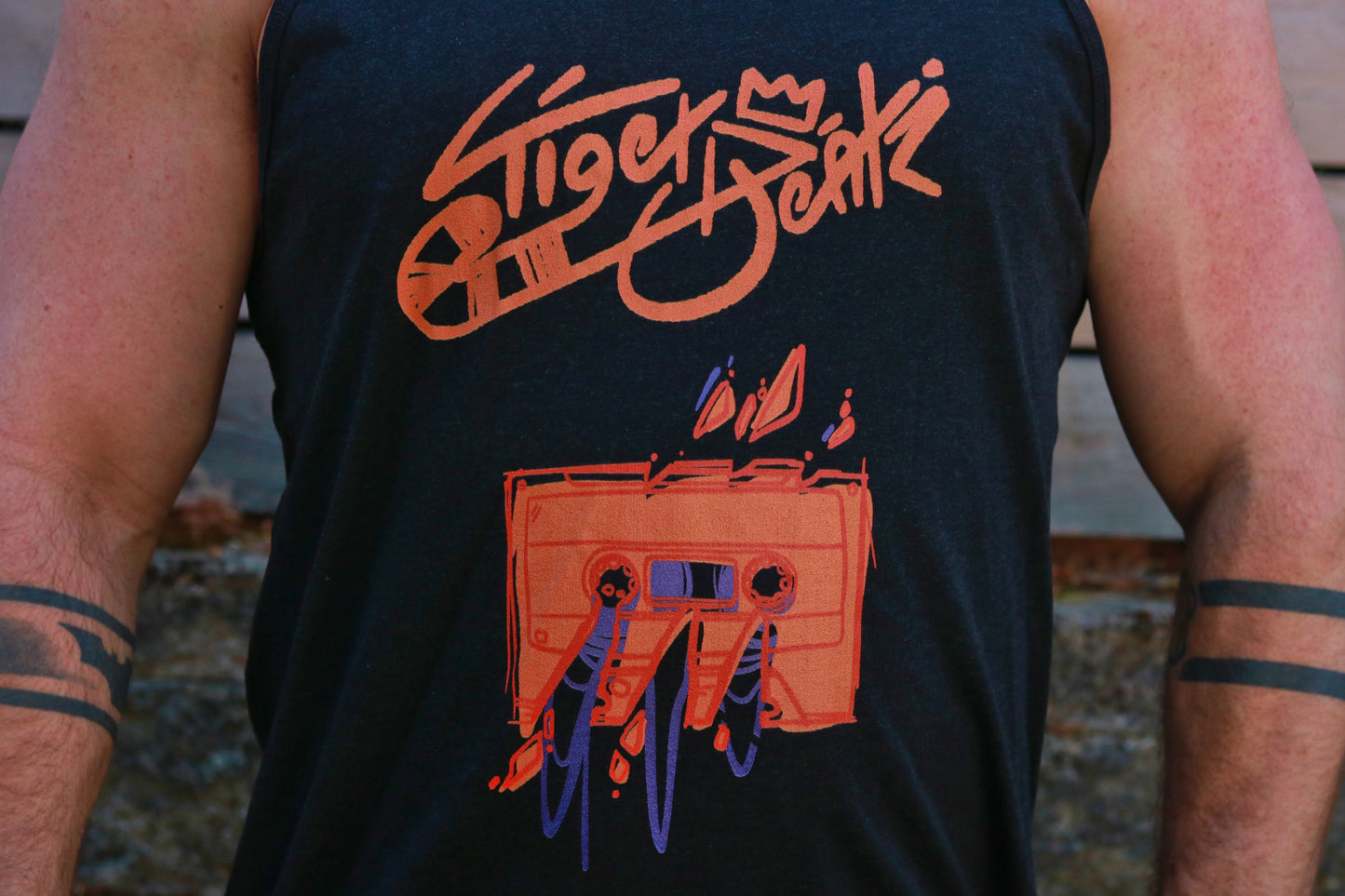 Black sleeveless shirt with orange graphic design and text on a person wearing it.