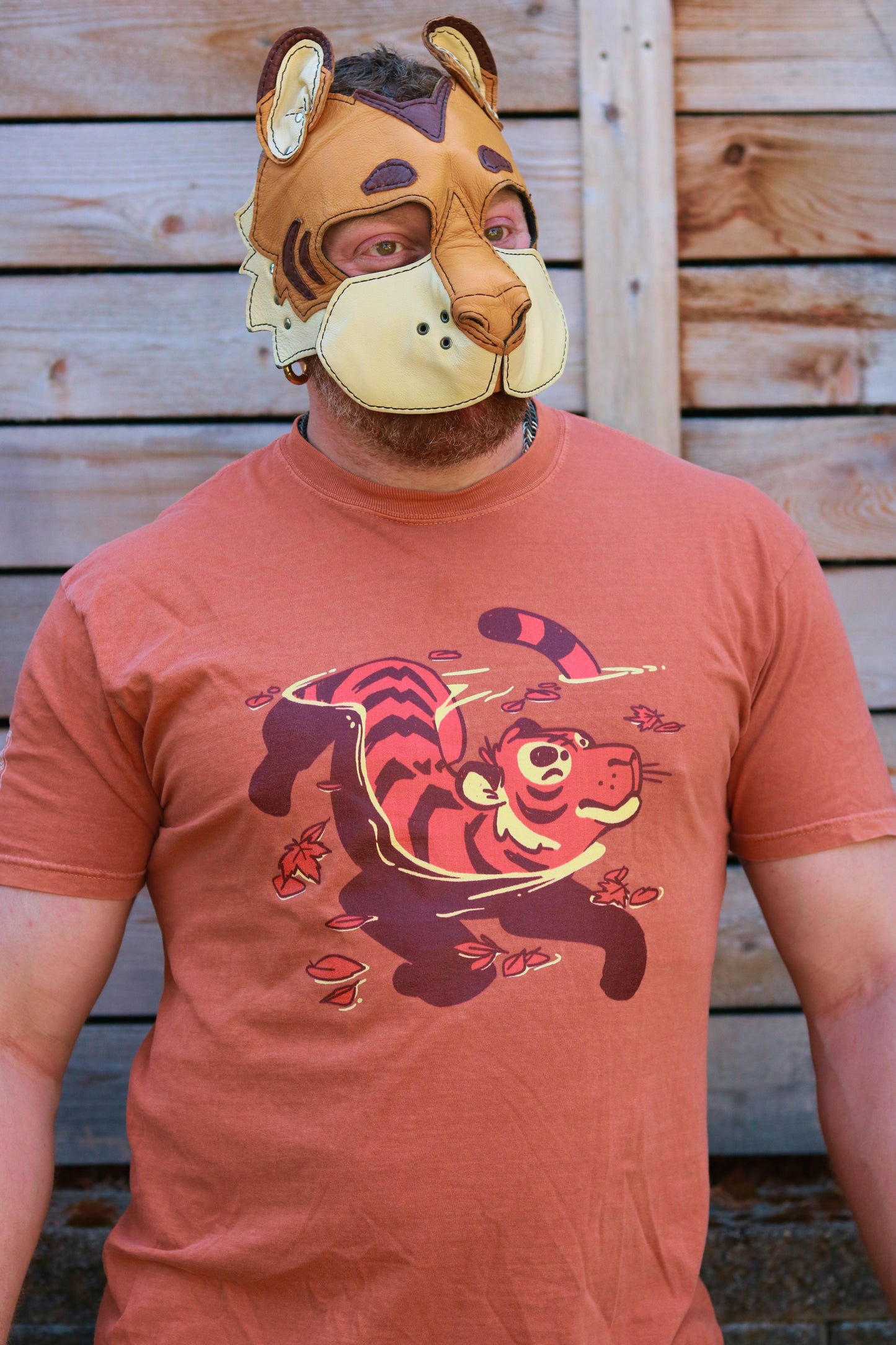 Person wearing a tiger-themed t-shirt and mask against a wooden background