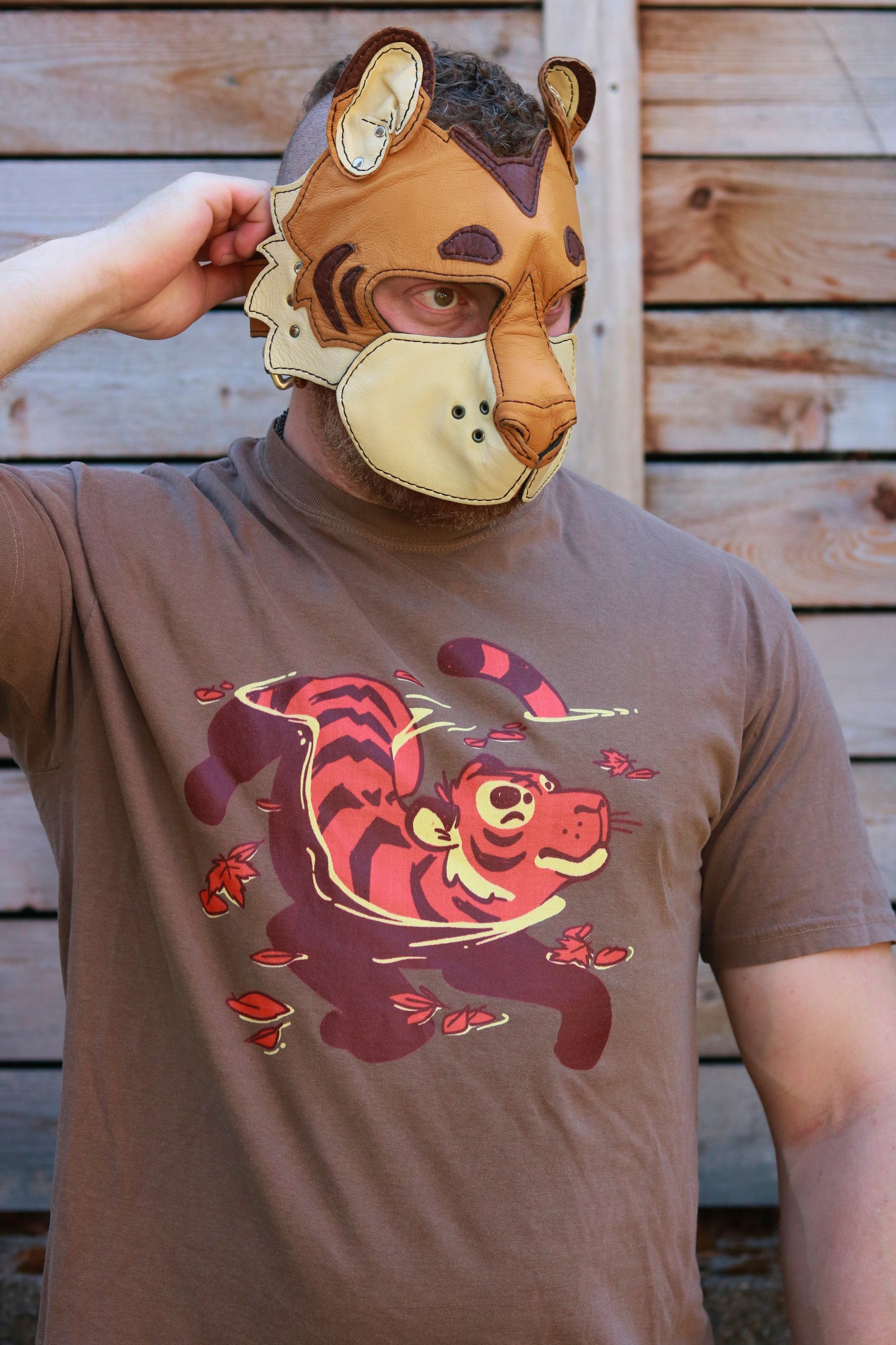 Person wearing a tiger-themed t-shirt and mask against a wooden background