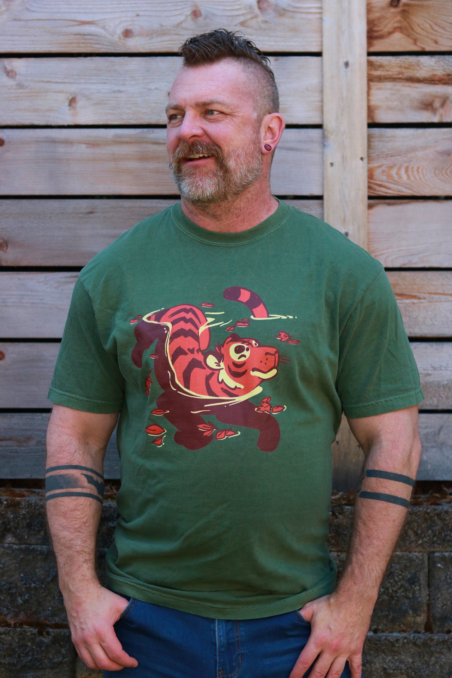 Man wearing a green t-shirt with a tiger graphic against a wooden background