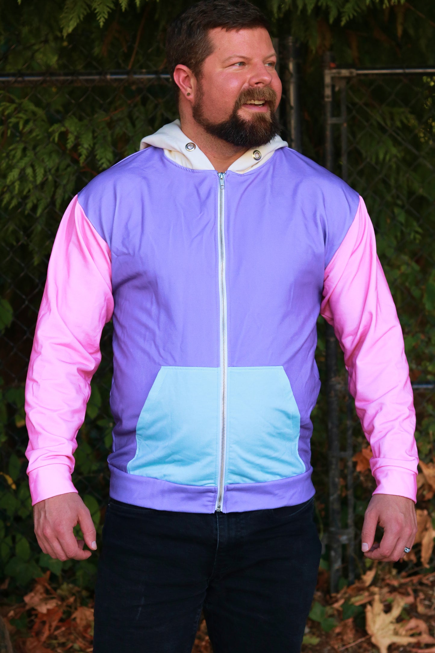 Man wearing a colorful jacket with pink sleeves and a gradient design, standing outdoors.