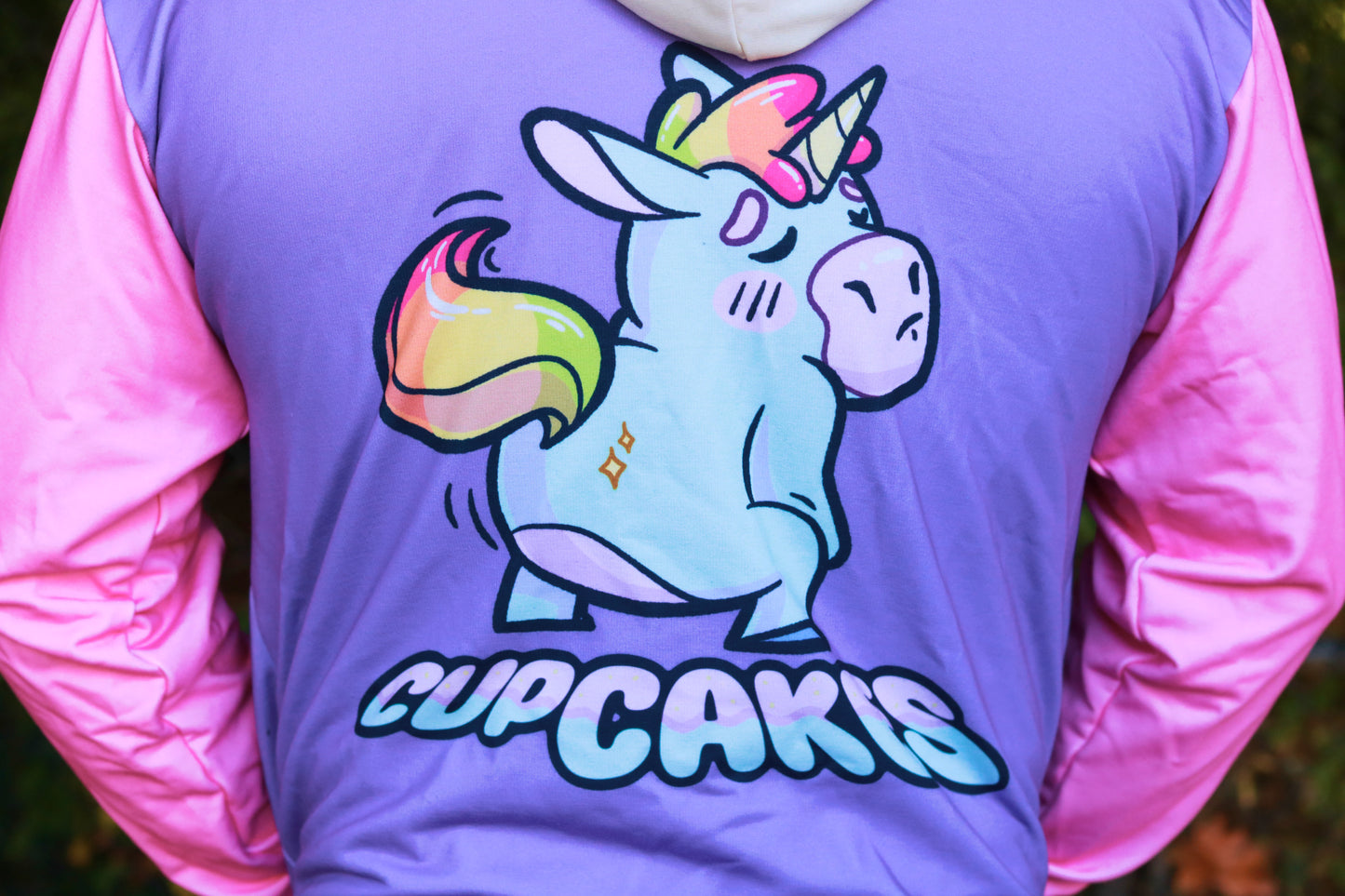 Person wearing a jacket with a colorful unicorn graphic and 'Cupcakies' text.