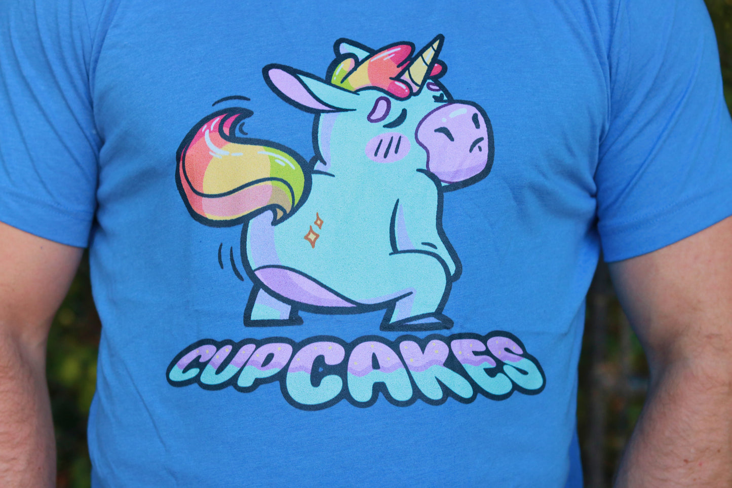 Blue t-shirt with a colorful unicorn graphic and 'CUPCAKES' text on a person wearing it.