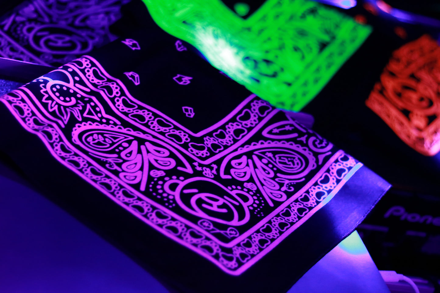 neon animal bandanas laid out together lit under black light.
