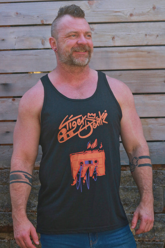 Man wearing a black tank top with a graphic design against a wooden background