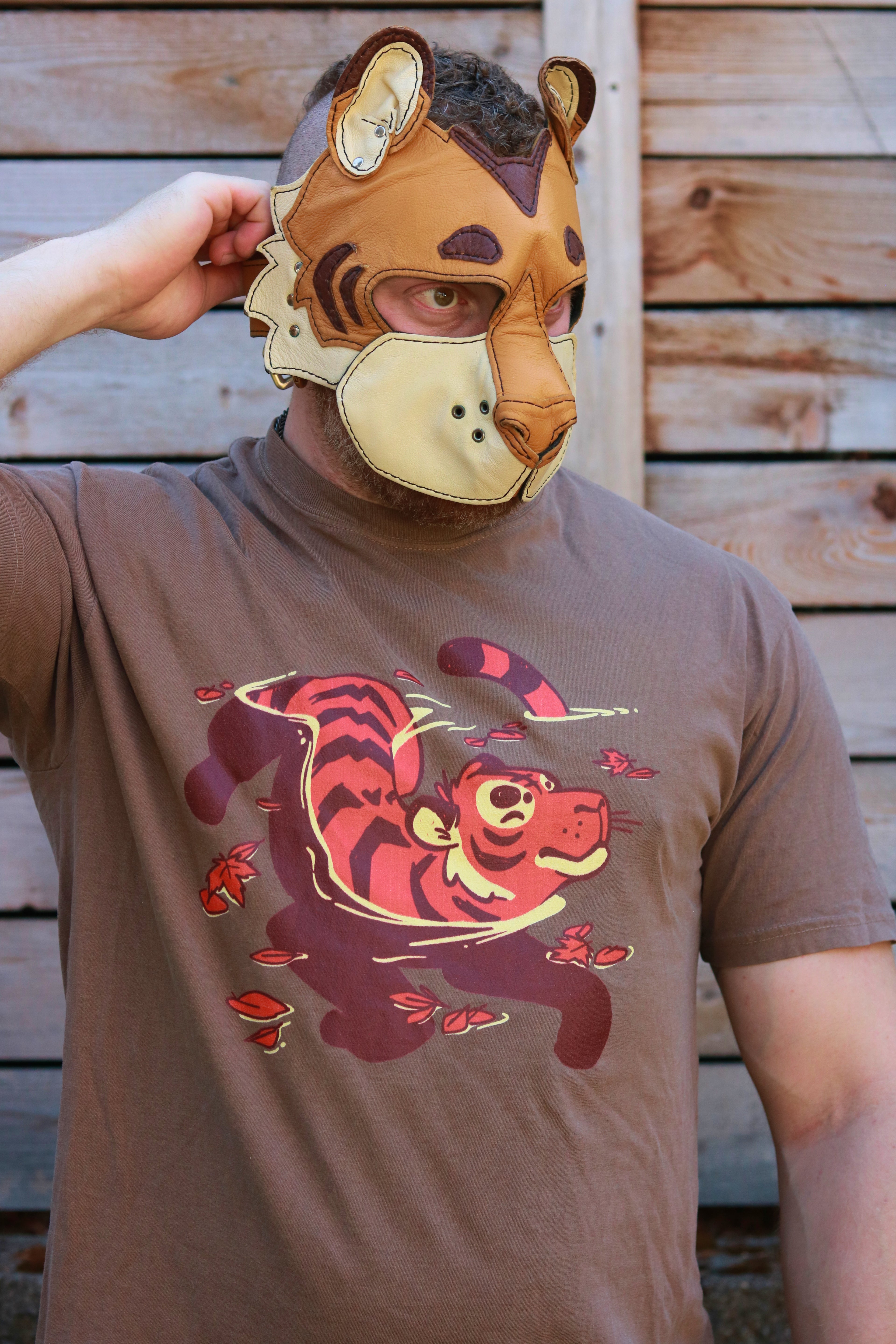 Person wearing a tiger-themed t-shirt and mask against a wooden background