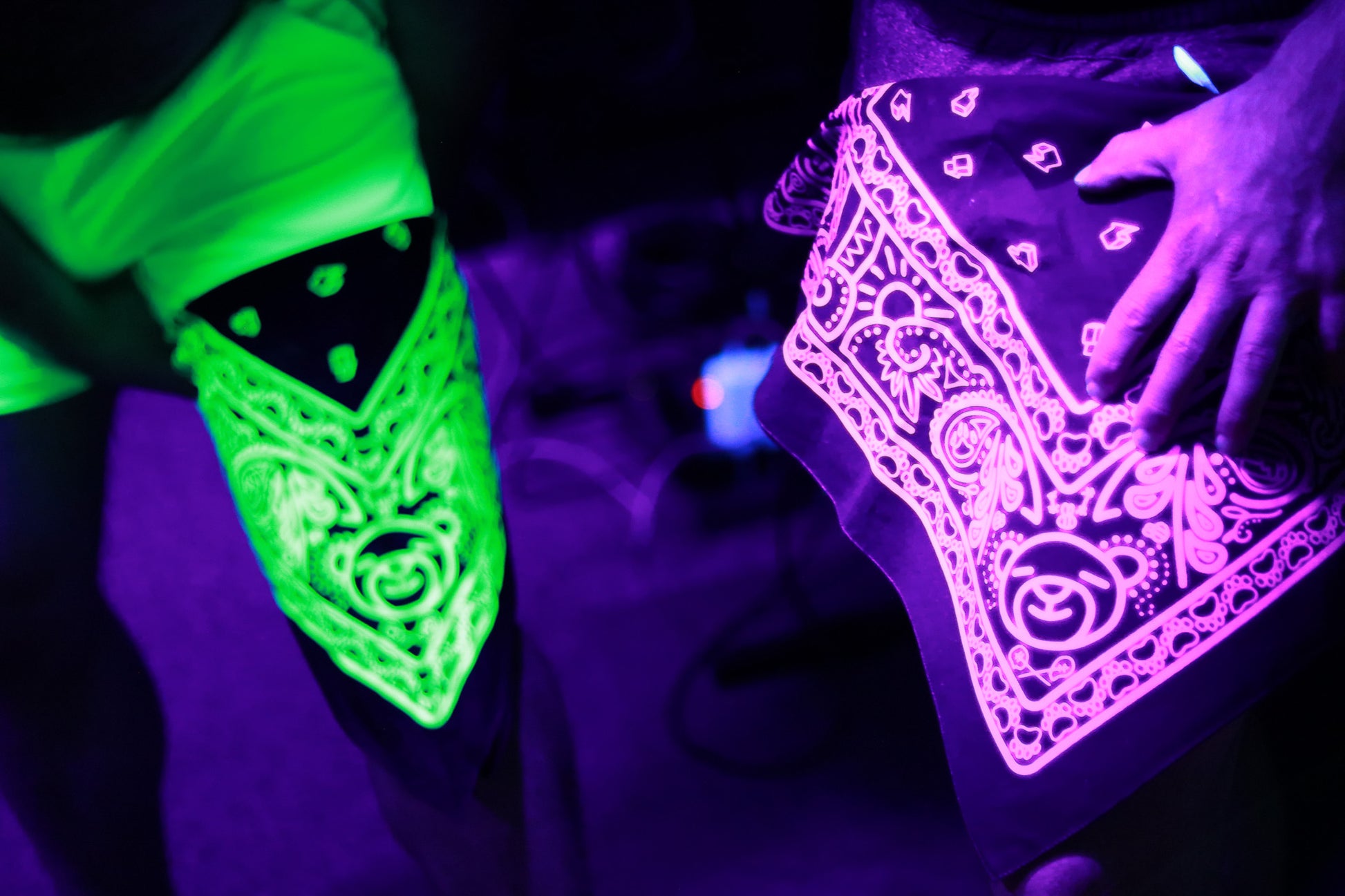 green and pink bandana held around pair of legs, lit by black light.