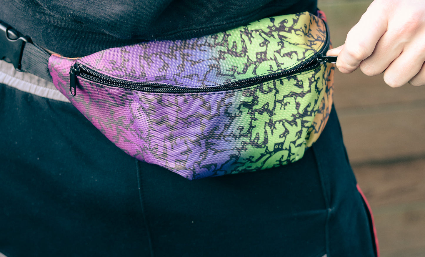 All over print fanny pack featuring rainbow bear pattern in style of Keith Haring being unzipped by hand