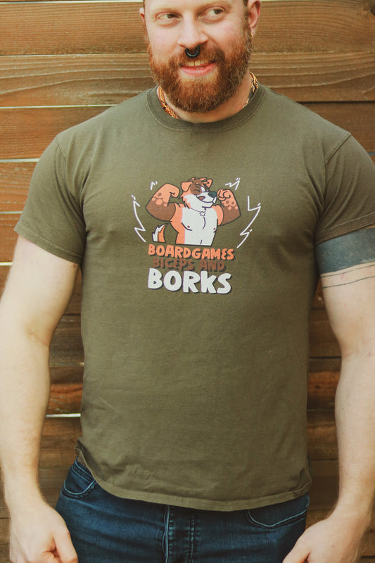 Ginger with beard wearing olive green shirt with furry orange and white dog art, text underneath "Boardgames Biceps and Borks"