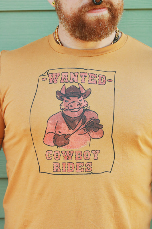 tan tshirt worn by bearded ginger with image of horse with riding crop and the the words "wanted, cowboy rides"